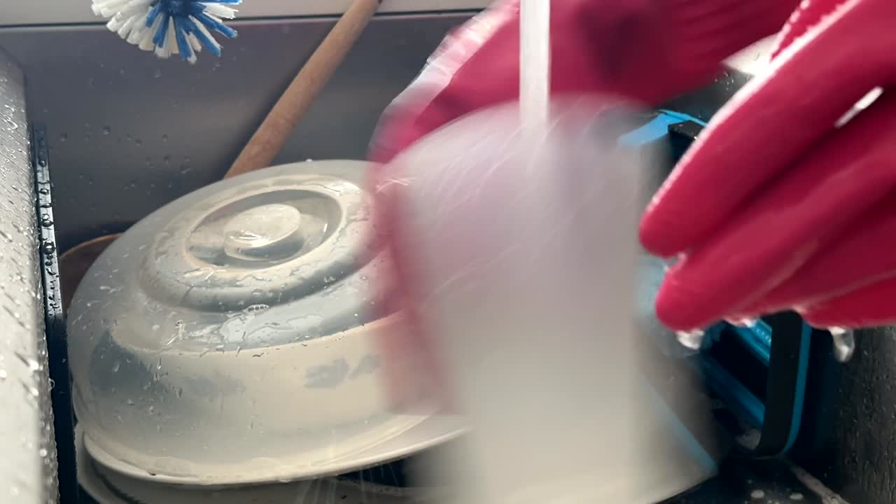 Busy Hands Washing Dirty Dishes In A Kitchen Sink