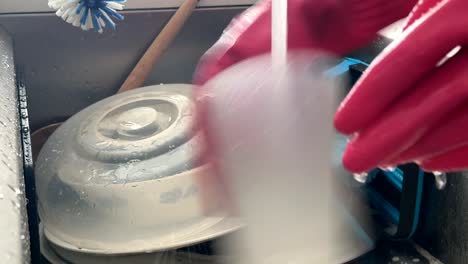 busy hands washing dirty dishes in a kitchen sink