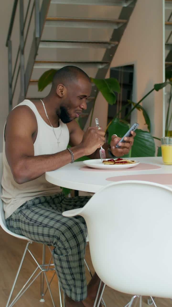 hombre comiendo panqueques y usando el teléfono