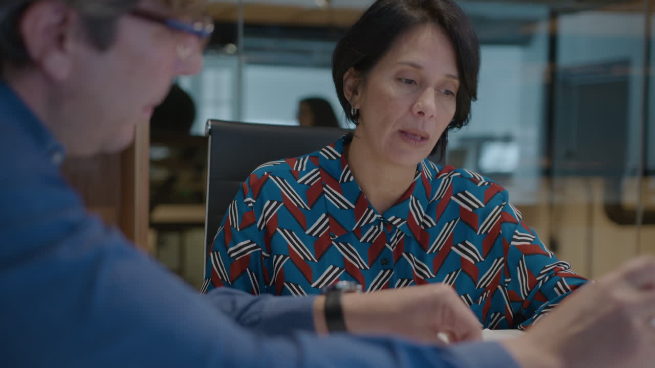 Mid-Aged Business Lady Discussing Documents with Coworker