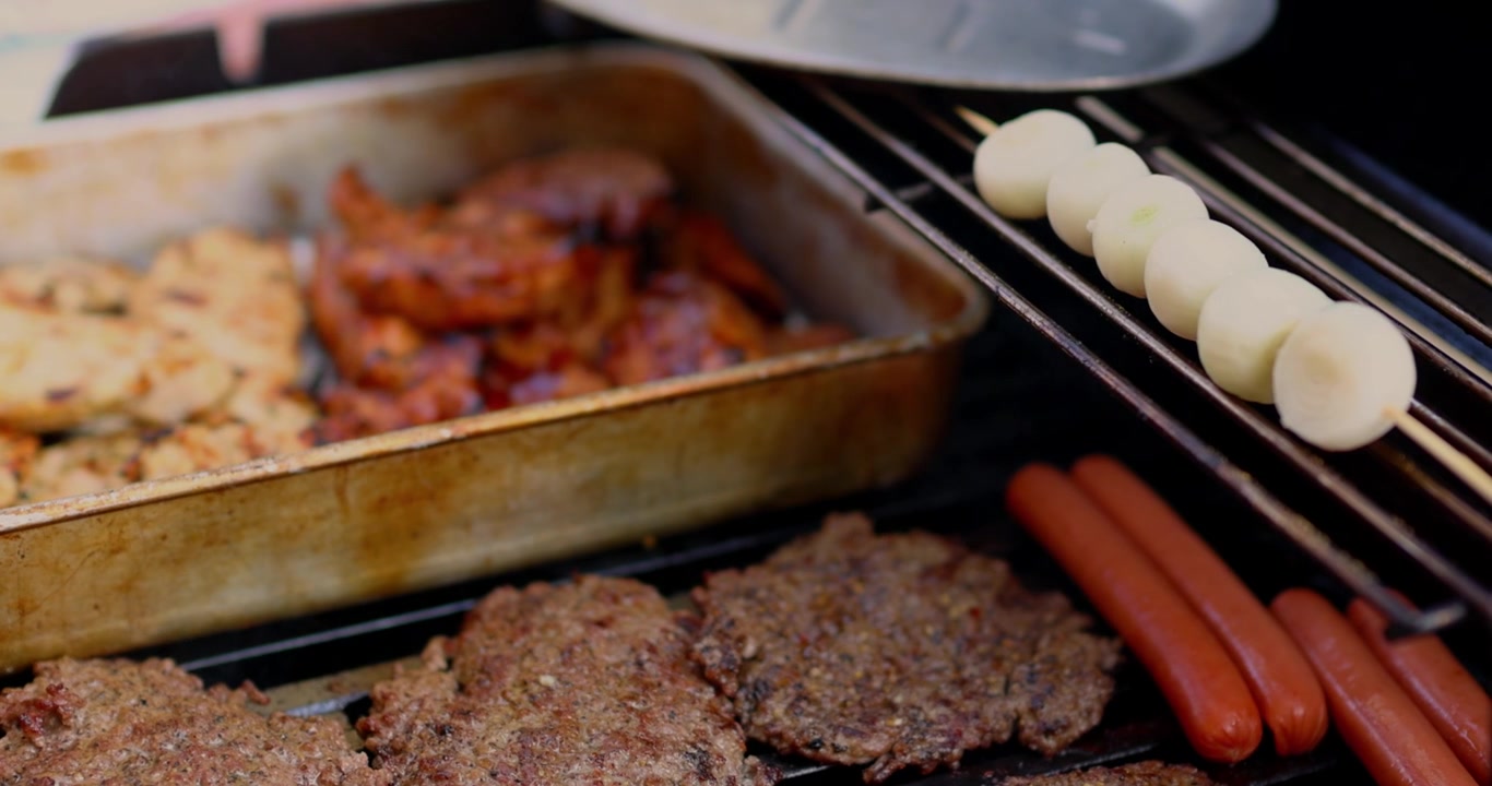 アメリカ合衆国建国250周年を祝う7月4日のバーベキューで、肉、鶏肉、牛肉、ホットドッグ、玉ねぎを調理しグリルする様子。シネマ4K 30fps（120fpsからスロー再生）。