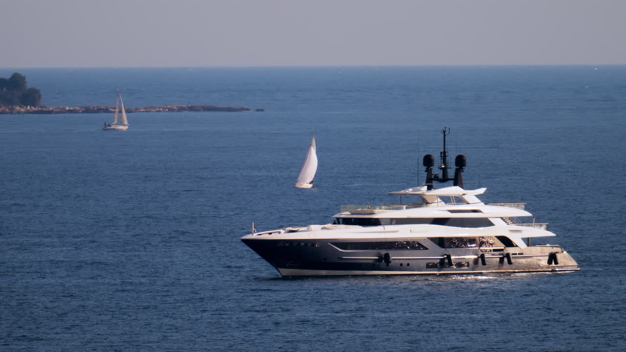 A white boat moving on the sea with other small boats on the background in the French Riviera