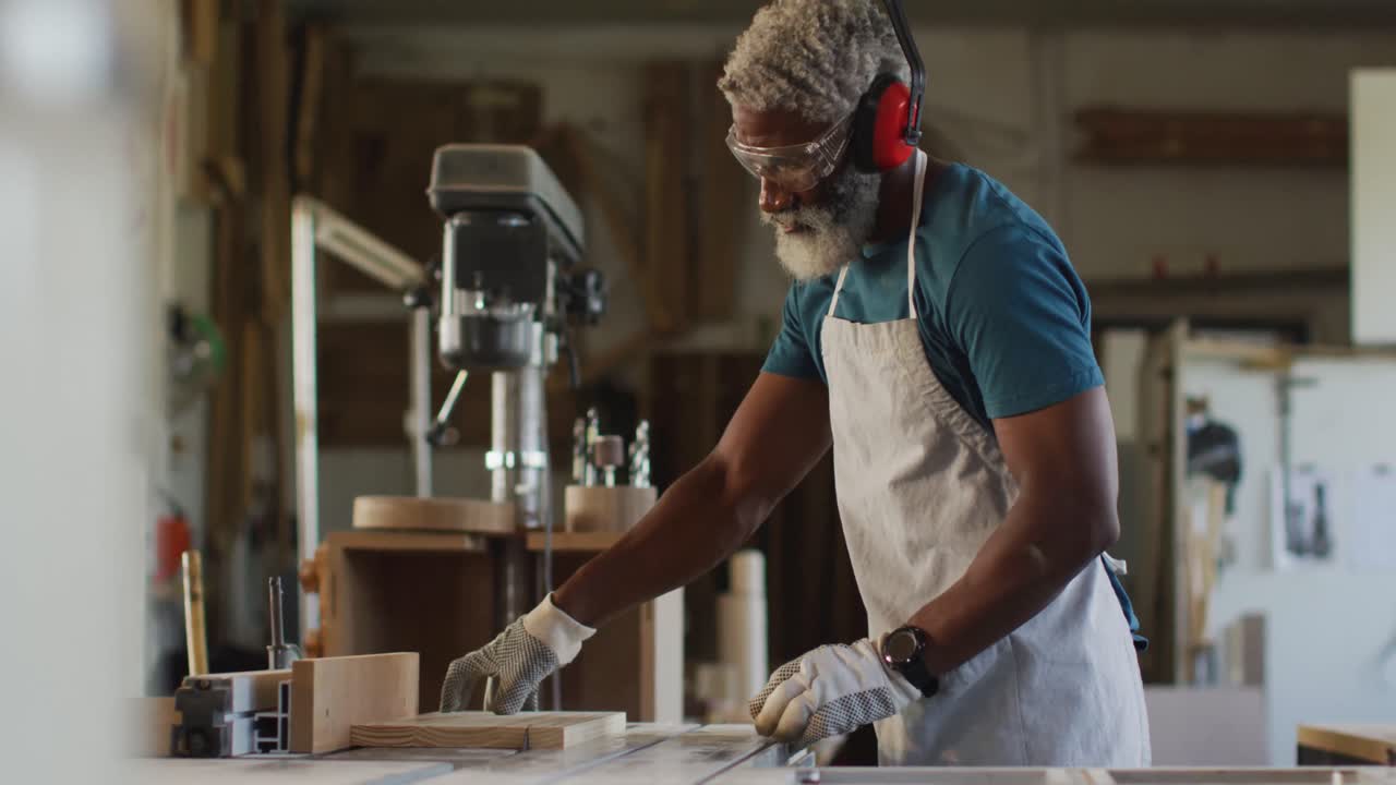 carpintero afroamericano que usa una sierra de mesa para cortar madera en una carpintería