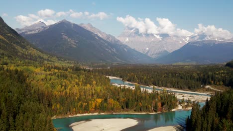 fantastischer dolly nach vorne zoomaufnahme des mount robson provincial park im herbst an einem tag mit einer mischung aus sonne und wolken mit bergen im hintergrund und dem fraser river davor, umgeben von wald