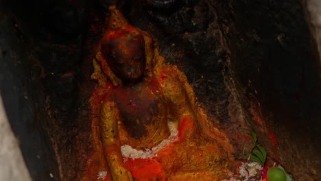 Tilting-clip-moving-to-close-up-of-a-shrine-containing-golden-statue-of-Buddha-surrounded-by-flower-offerings