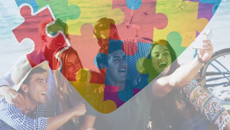 animation of colourful puzzle pieces heart over happy friends at summer beach party