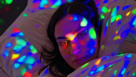 woman relaxing with colorful light patterns on her face