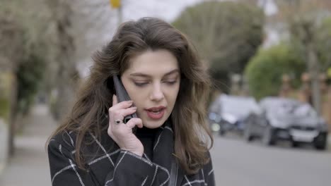 mujer de negocios segura y sonriente hablando por teléfono al aire libre en city street londres central
