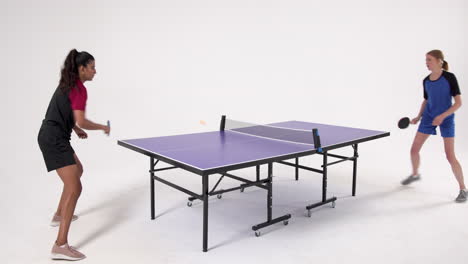 playing table tennis, two women competing in match with paddles and ball