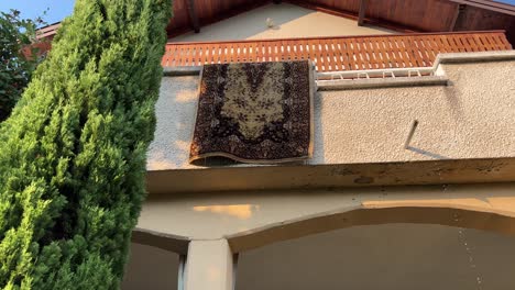 drying washed carpet on a terrace railing of a house