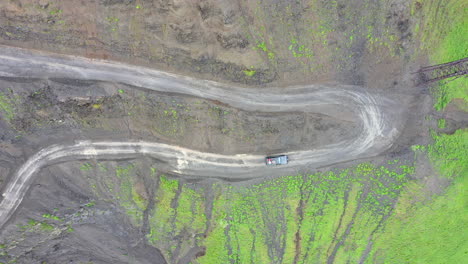 Downward-angle-descending-drone-shot-of-vehicle-driving-on-the-Road-to-Tusheti,-one-of-the-worlds-most-dangerous-roads