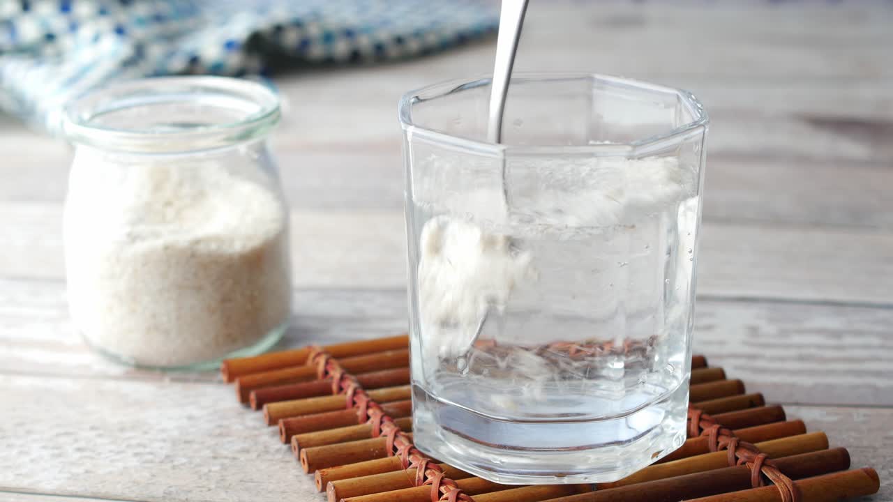 Spoon stirring psyllium seeds in a glass of water
