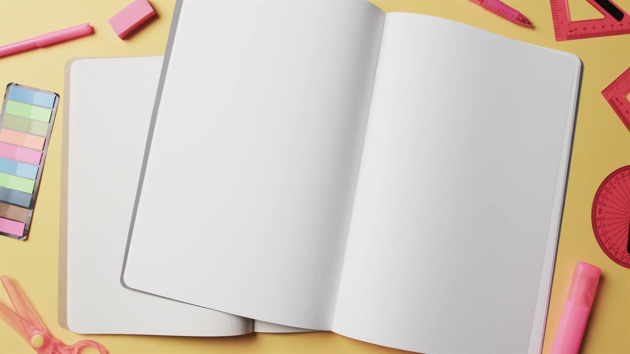 Overhead view of open notebooks with school stationery on beige background, in slow motion