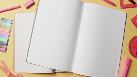 overhead view of open notebooks with school stationery on beige background, in slow motion