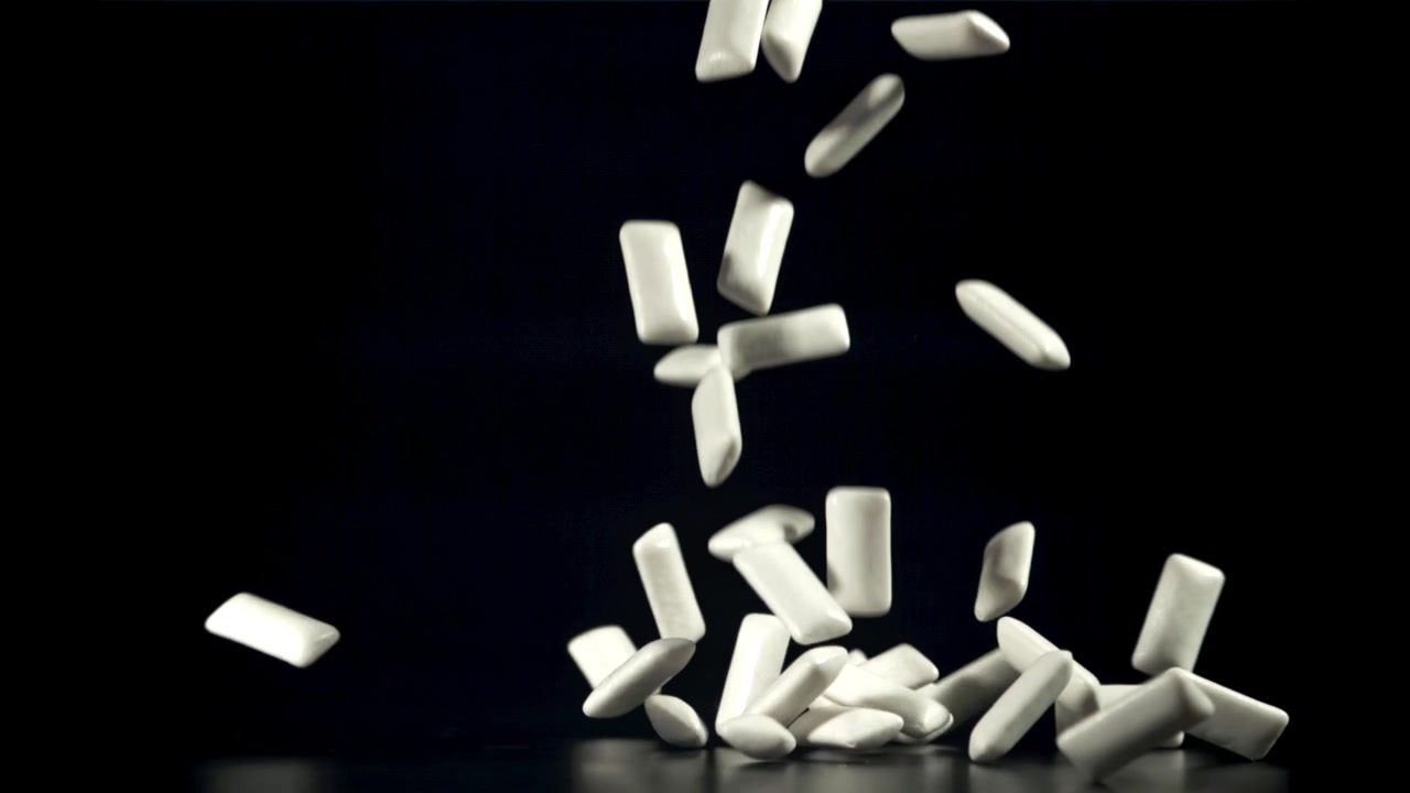 Pezzi di gomma da masticare bianca che cadono in slow motion su uno sfondo nero