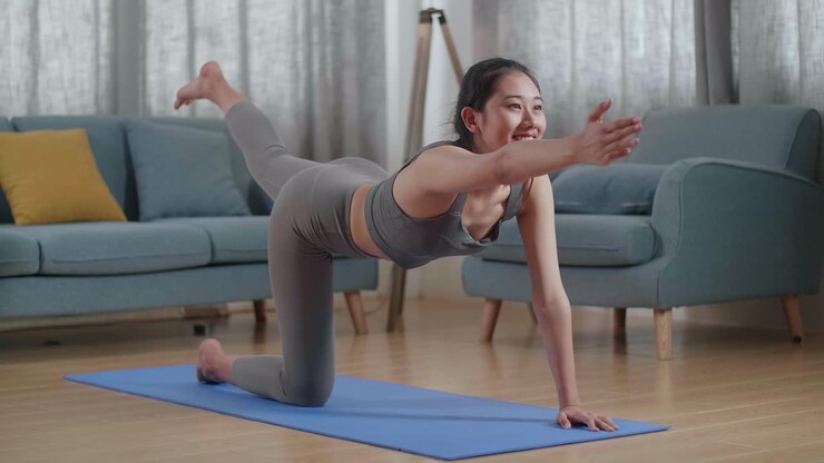 Young Asian Athletic Female In Sports Clothes Doing Yoga In Balancing Table Pose On The Mat At Home