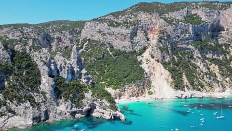 Los-Barcos-Turísticos-Disfrutan-De-Las-Vacaciones-De-Verano-En-La-Playa-De-Cala-Goloritze-Y-La-Formación-Rocosa-En-Cerdeña,-Italia---Antena-4k