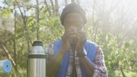 Afroamerikanischer-Mann-Im-Wald,-Der-Tee-Auf-Dem-Land-Trinkt