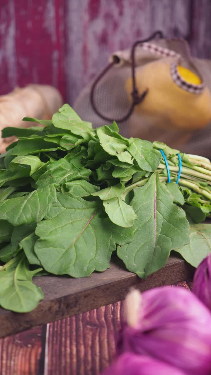Rucola fresca, cipolle rosse e spezie su un tavolo di legno