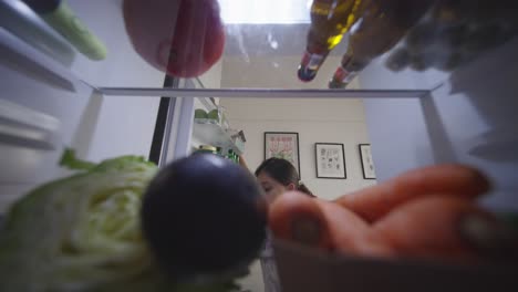 woman looking inside refrigerator at night