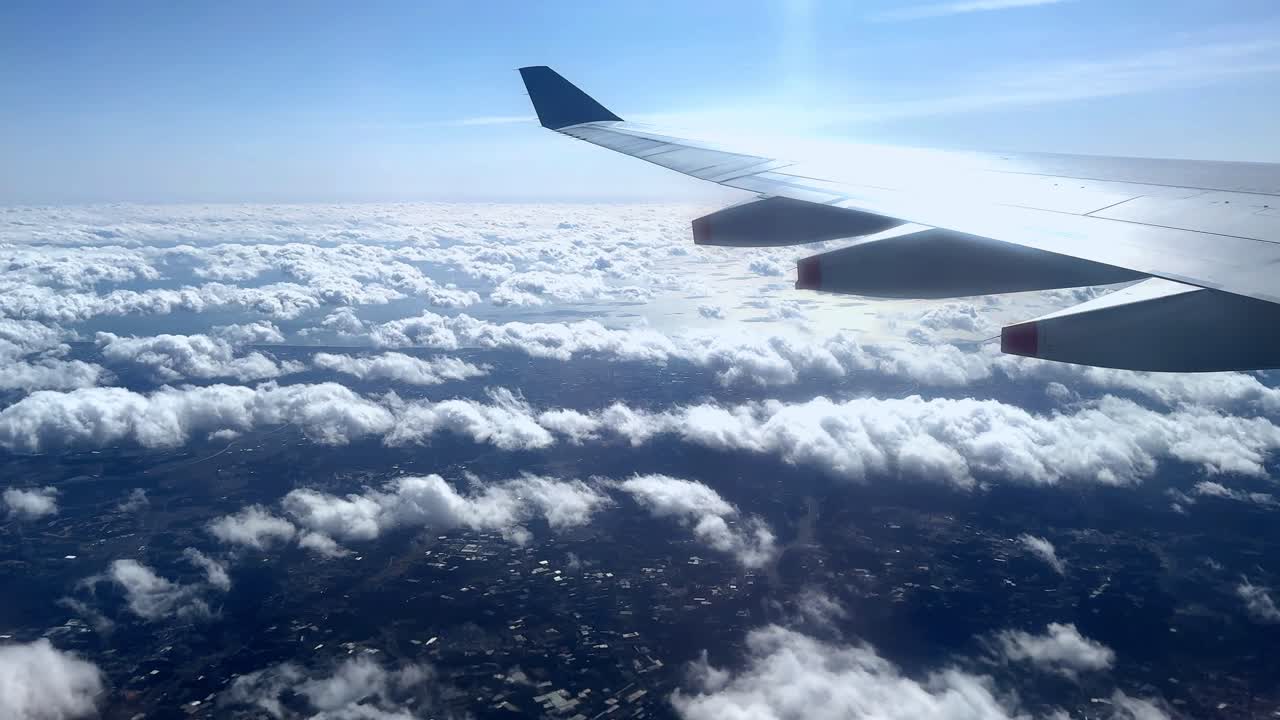 Flyvinge over et skybeklædt landskab, solrig himmel, fjern horisont.