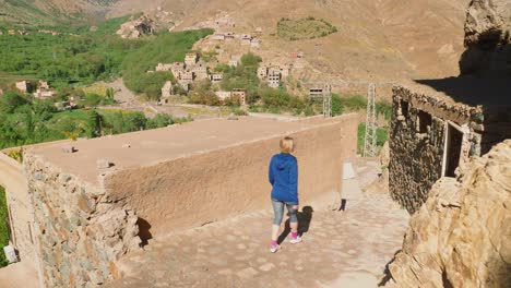 blonde tourist girl exploring moroccan rural houses in imlil, high atlas, morocco