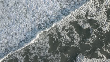 diagonal shot of foamy surf waves roll over ocean during sunset in summer at long beach island, new jersey, usa