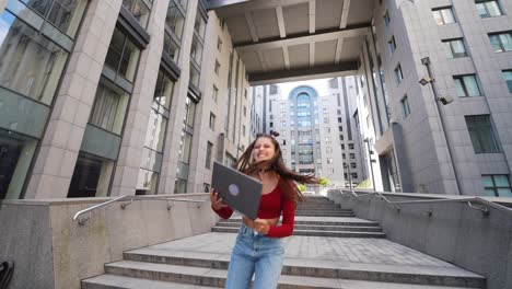 mujer celebrando el éxito al aire libre con una computadora portátil