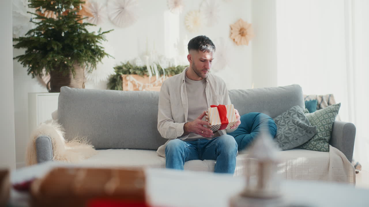 슬픈 남자가 크리스마스 선물을 열고 외롭고 우울한 느낌을 느다.