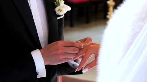 during the wedding ceremony, the groom puts a gold ring on the bride's finger