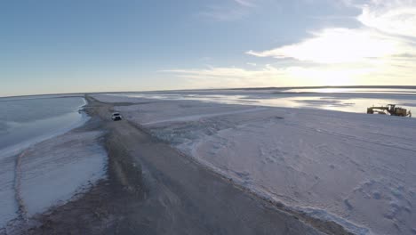 Aerial-rolling-drone-shot-shot-of-a-pickup-in-the-salt-flats-by-solar-evaporation-in-Guerrero-Negro,-Ojo-de-Liebre-lagoon,-Biosphere-Reserve-of-El-Vizcaino,-Baja-California-Sur