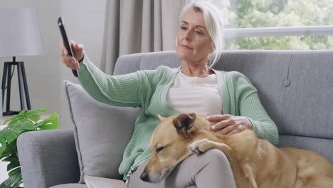 Senior-woman-watching-tv-and-sitting-on-a-couch