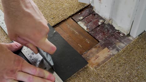 Cutting-carpet-tile-with-blade-and-metal-ruler-to-fit-around-doorframe