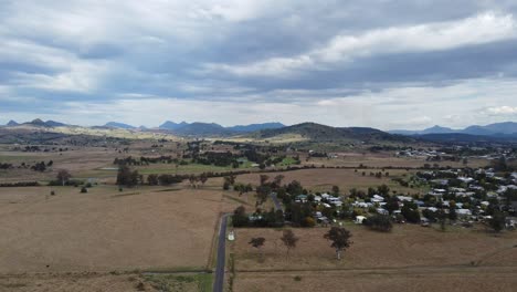 volando sobre un camino rural hacia un pequeño pueblo y montañas