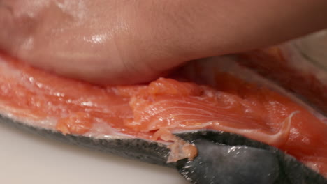 a skilled chef slicing and separating spine bones on the fresh meat of salmon for sushi