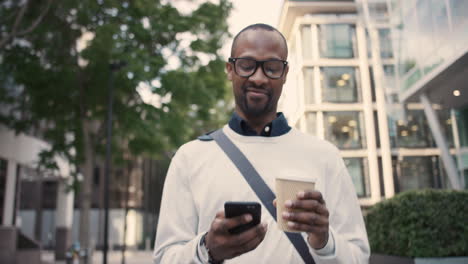 african american businessman walking through city using smart phone