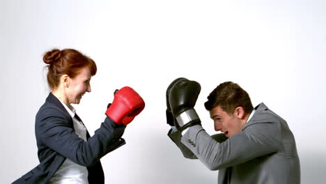 joven mujer de negocios golpeando a un colega con guantes de boxeo