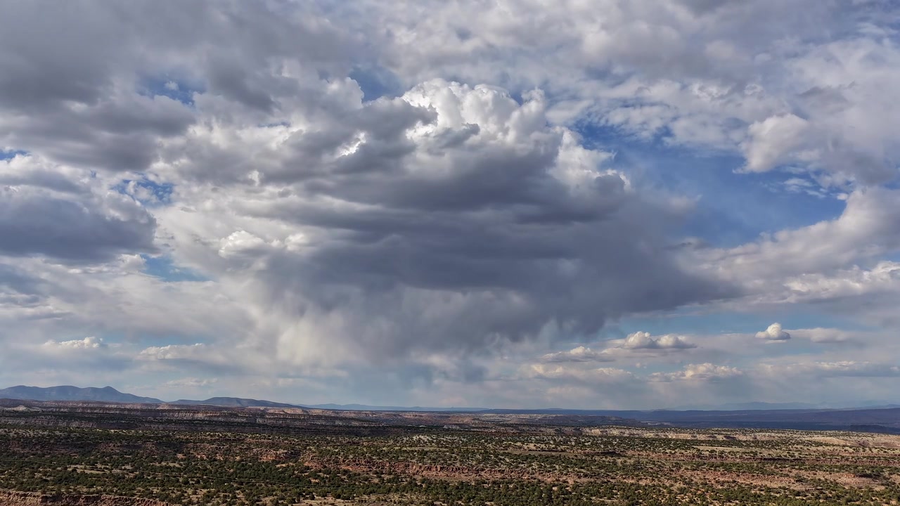 Timelapse aereo stabile di una dinamica nuvola di pioggia che si trasforma su vaste mesas desertiche. Ombre mutevoli e rovesci di pioggia localizzati evolvono splendidamente attraverso il paesaggio aspro del sud-ovest.
