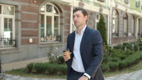 Closeup-man-walking-with-coffee-outdoor.-Man-drinking-coffee-before-work