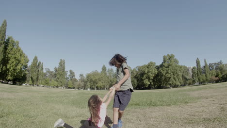 long shot of happy brother circling little sister around on lawn