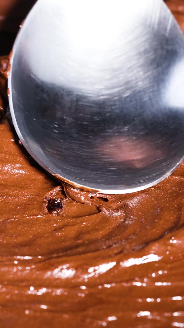 Cucchiaio che mescola ricca e cremosa pastella al cioccolato