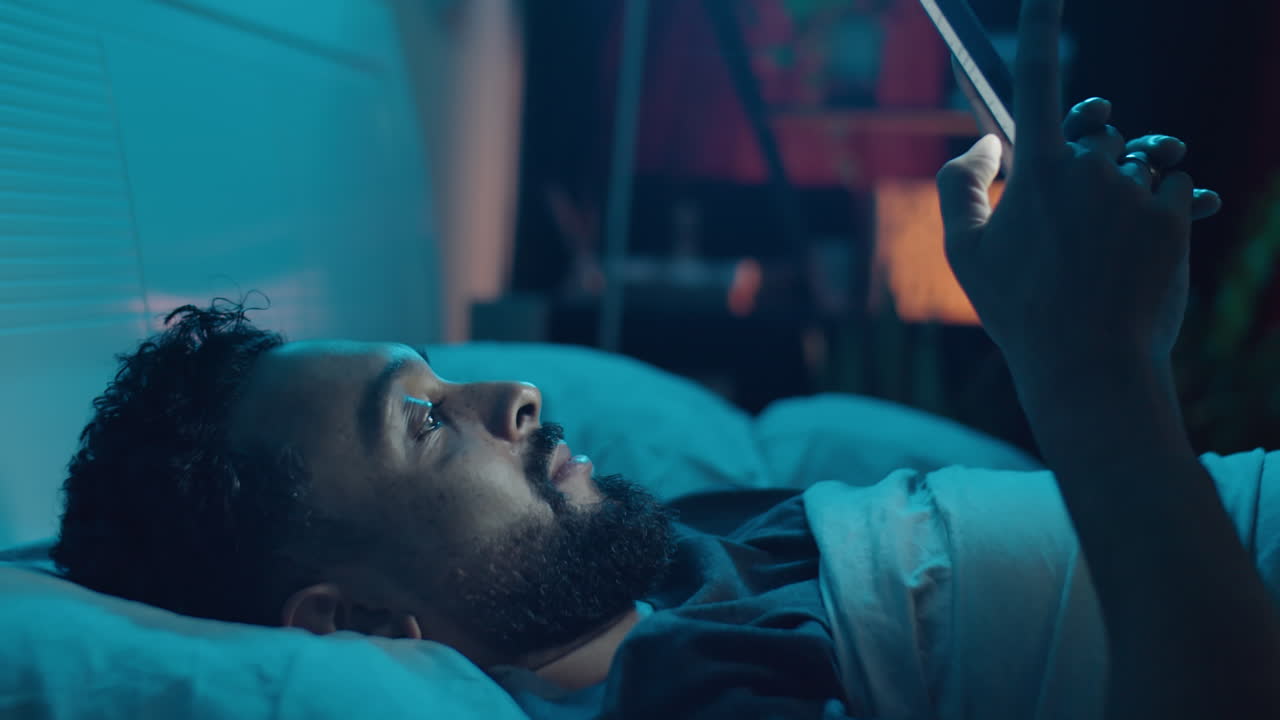 Uomo che usa lo smartphone a letto di notte