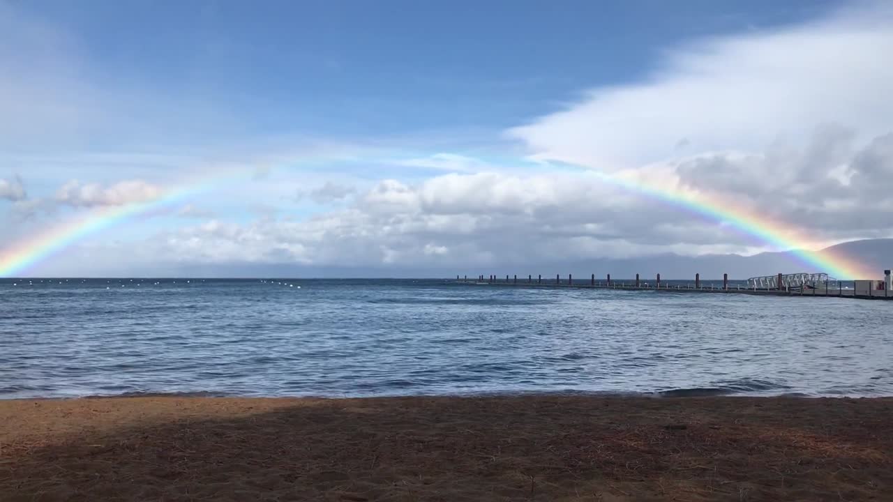 un arco iris completo sobre el horizonte del agua en lake tahoe, california.