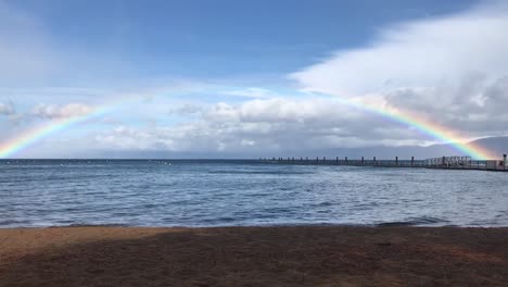 a full rainbow above the horizon of the water in lake tahoe, california