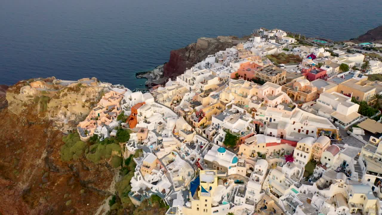 increíble video del famoso pueblo pintoresco blanco y colorido de oia construido sobre un acantilado al atardecer, isla de santorini, cícladas, grecia