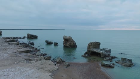 Aerial-view-of-abandoned-seaside-fortification-buildings-at-Karosta-Northern-Forts-on-the-beach-of-Baltic-sea-,-overcast-day,-wide-drone-shot-moving-forward,-camera-tilt-down