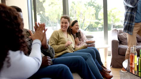 happy diverse male and female friends watching sport on tv and celebrating victory