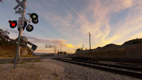 Wide-shot-of-a-train-track-and-railway-track-as-the-signal-and-red-lights-flash-and-the-gates-close-to-protect-traffic-from-crossing-the-tracks