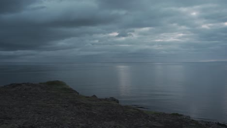 una maravillosa vista panorámica en hora azul después de la puesta de sol del increíble paisaje marino filmado desde un acantilado en islandia que también muestra kirkjufell