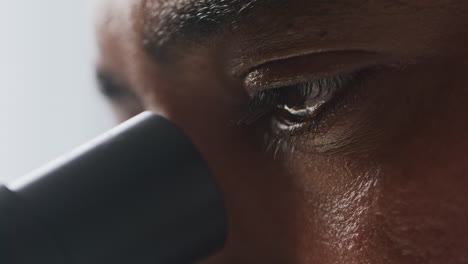 observing sample through microscope with intense concentration